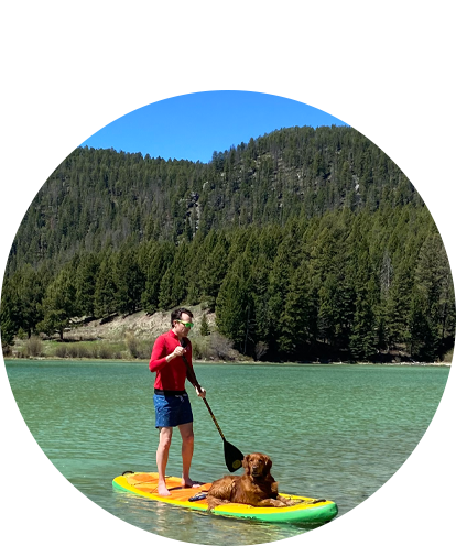 Darryle Ish Fun Photo (adult male on paddle board with red golden retriever sitting on front while paddling on mountain lake during a blue sky summer day).