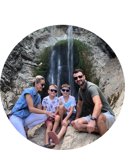 Adisa Kulasic fun photo posing with husband and two children in front of a waterfall.