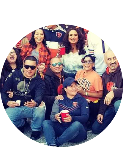 Honey Beth Jucaban fun photo posing on bleachers with 7 adults smiling at sports or concert event.