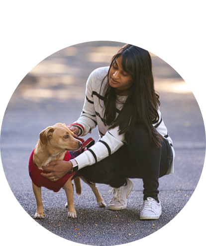 Karishma Thakkar fun photo crouching down and petting small dog.