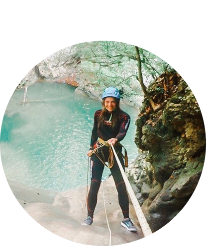 Melody Dawkins fun photo repelling off of a cliff with body of water in background.