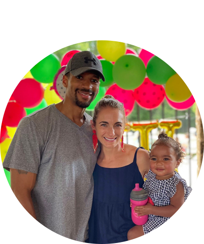 Jaron Franklin posing with femail and young toddler with balloons in the background.