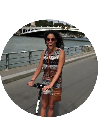 Sarah Williams fund photo on standup scooter with river and bridge in background.