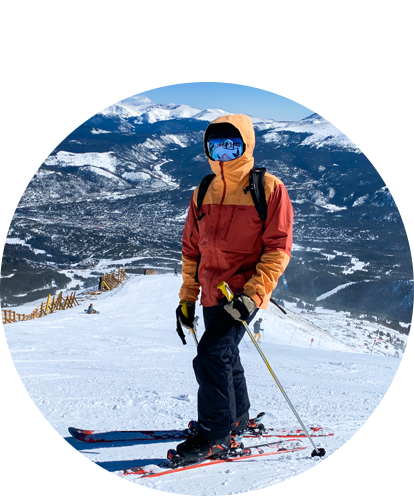 Ben Wojtynek fun photo posing on top of ski slope wearing ski outfit and skis.