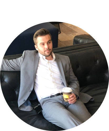 Joseph Opalensky fun photo adult male sitting on leather sofa in suite without a tie holding a cup of coffee.