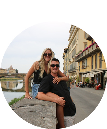 Phillip Friedman fun photo posing with adult female on river edge wall in an old world city.