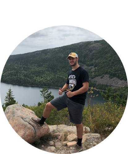 John Deseno fun photo posing on hilltop with water and trees in background.