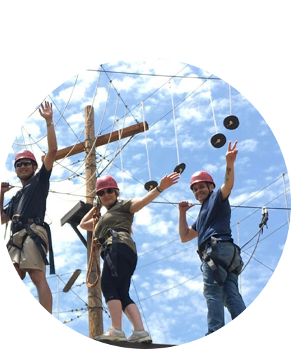 Roberto Hatch fun photo (three humans scaling an elevated ropes and obstacle course on a sunny day).