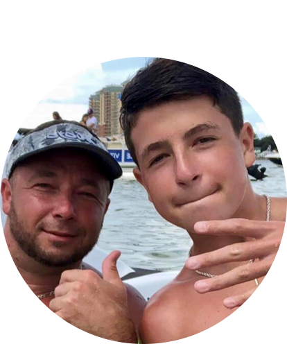 Dusty Land fun photo (adult male posing with teenage male outdoors with body of water in background).