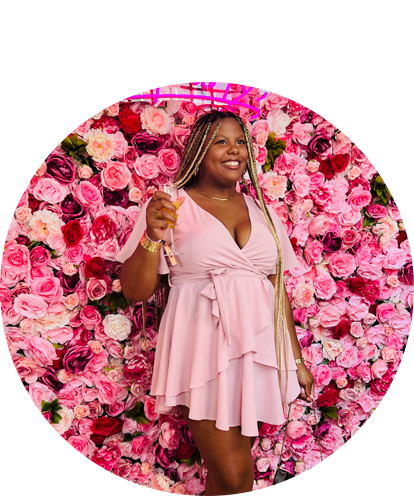 Bretagne Ball fun photo (adult female posing behind wall of flowers wearing a dress with drink in hand).