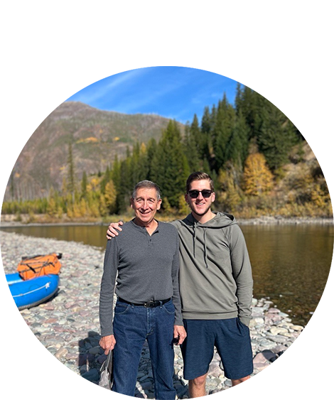 Man smiling next to a lake with father.